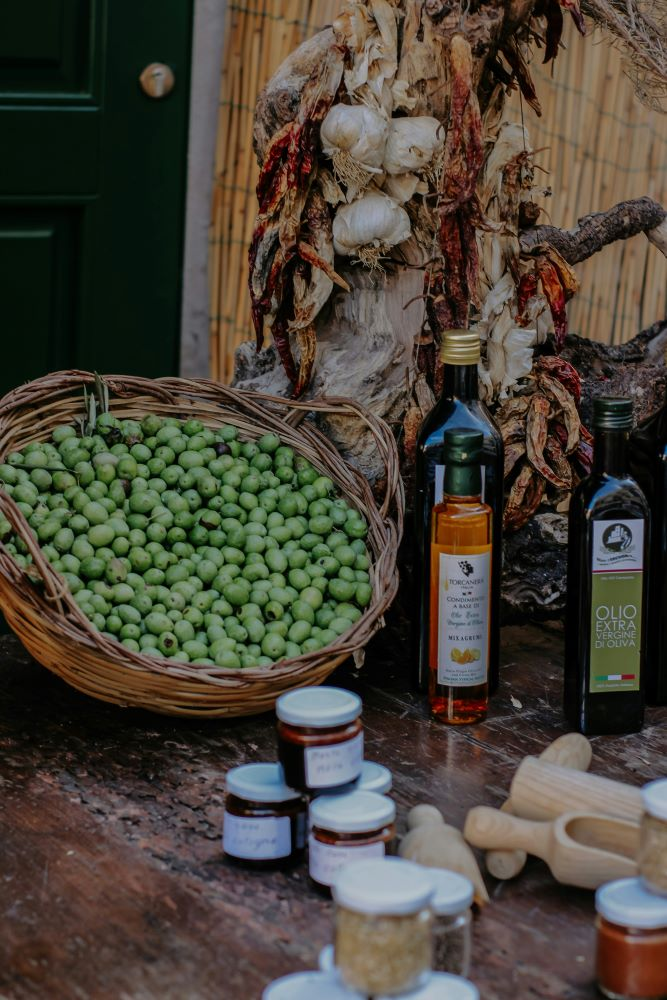 assorted bottles of extra virgin olive oil with fresh olives on a rustic wooden table