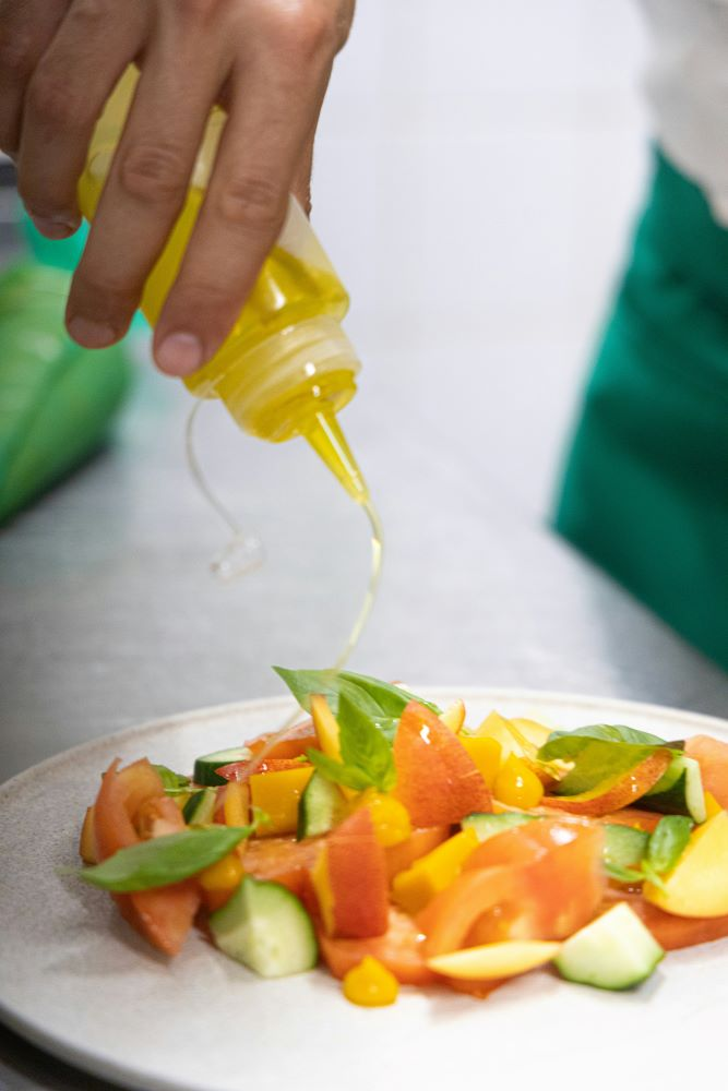 pouring olive oil over salad, highlighting heart healthy benefits